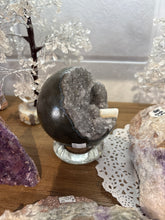 Load image into Gallery viewer, Side view of hand-polished Brazilian amethyst geode sphere displaying grey amethyst crystals and natural white calcite with smooth dark polished exterior