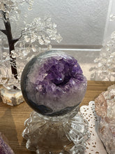 Load image into Gallery viewer, Close-up view of dark purple amethyst crystals inside polished geode sphere from Brazil