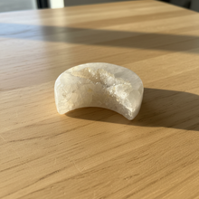 Load image into Gallery viewer, Angled view of Brazilian agate moon geode with luminous translucent white agate and warm cream druzy cavity, 8cm x 4.5cm crescent moon carving