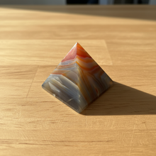 Load image into Gallery viewer, Side view of Brazilian agate pyramid showing the graceful flowing banding in warm orange, cool grey-blue, and creamy white natural agate
