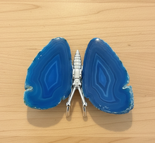 Load image into Gallery viewer, Brazilian agate butterfly specimen with vibrant blue banded wings displayed on wood table, front view showing natural stone patterns and color variations