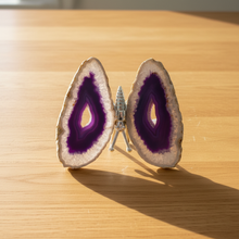 Load image into Gallery viewer, Brazilian agate geode butterfly specimen with vibrant purple centers and sparkling white crystal edges displayed on wood table, front view showing natural geode cavities