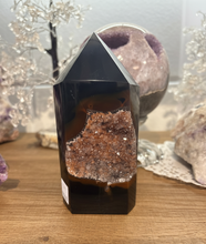 Load image into Gallery viewer, Polished Brazilian agate tower with natural two-tone brown banding and druzy crystal pocket displayed upright on mid-tone wood surface