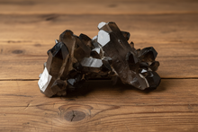Load image into Gallery viewer, Brazilian smokey quartz crystal cluster side view displaying layered architecture and rich smoky coloring from charcoal to honey tones on wood surface