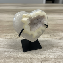 Load image into Gallery viewer, Uruguay agate heart specimen showing natural translucent banding layers and quartz druzy crystals on black stand, side view