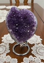Load image into Gallery viewer, Angled view of Uruguayan amethyst heart on silver display stand highlighting crystal depth and formation

