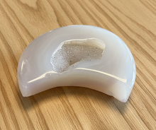 Load image into Gallery viewer, Angled view of Brazilian agate moon geode with luminous white agate and glittering druzy cavity, 8.5cm x 5cm crescent moon carving
