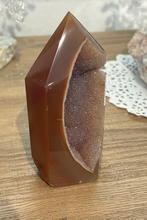 Load image into Gallery viewer, Angled view of polished agate geode point highlighting natural crystal-lined interior and smooth polished exteriornull---
