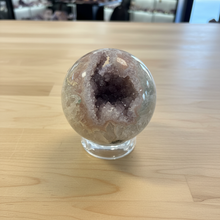 Load image into Gallery viewer, Front view of hand-polished rainbow amethyst geode sphere displaying purple and lavender druzy crystals with smooth polished exterior
