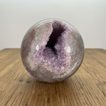 Load image into Gallery viewer, Multi-cavity rainbow amethyst geode sphere displaying two distinct purple amethyst crystal openings with translucent polished exterior

