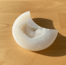 Load image into Gallery viewer, Side view of Brazilian agate moon geode carving showing the polished white exterior and natural crystal druzy center with subtle grey banding

