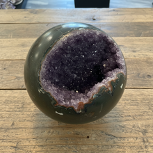 Load image into Gallery viewer, Top-down view of hand-polished amethyst geode sphere revealing deep purple amethyst crystal cavity with exceptional depth and sparkle
