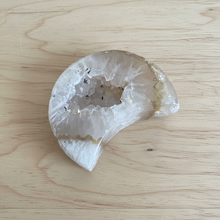Load image into Gallery viewer, White agate crescent moon with sparkling druzy crystal cavity center on light wood table, showing translucent quality and natural inclusions
