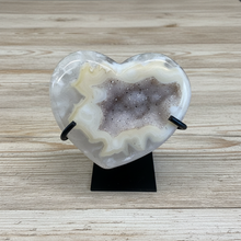 Load image into Gallery viewer, Uruguay agate heart geode with cream and white banding and sparkling druzy crystal center on black display stand, front view
