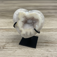 Load image into Gallery viewer, Uruguay agate heart geode displaying intricate cream banding patterns and sparkling crystal cavity on display stand, angled view
